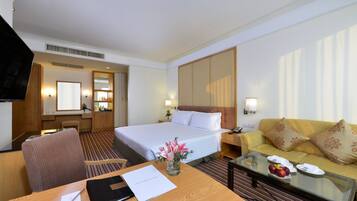 A hotel room with a bed, a sofa, a desk, and a TV.