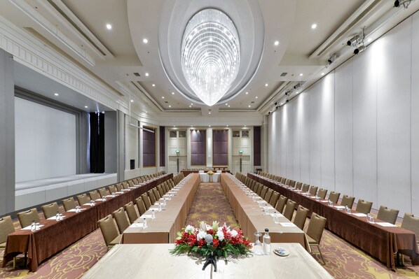 A large conference room with a long table, rows of chairs, and a chandelier. - Miracle Grand Convention Hotel (Bangkok)