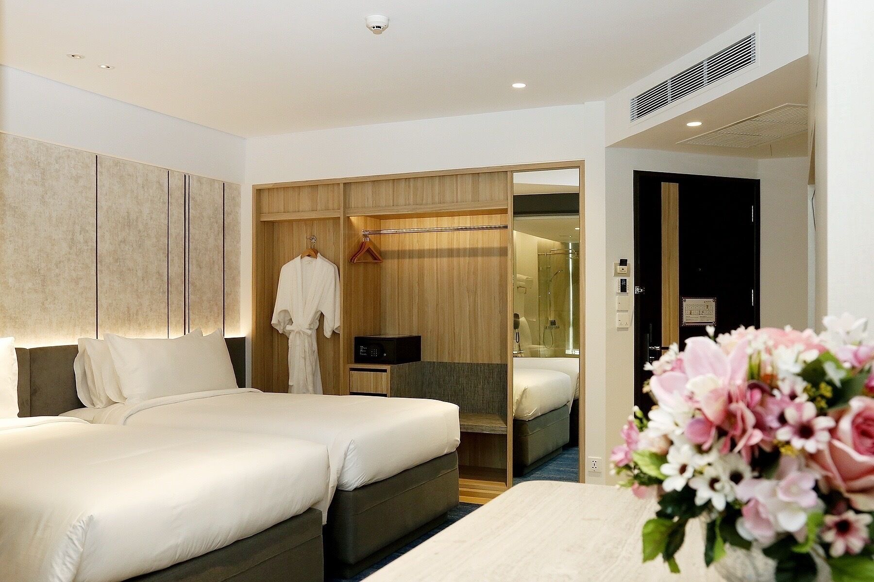 A hotel room with a large bed, a walk-in closet, a bathroom with a shower, and a small desk.