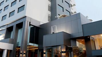 A modern hotel with a prominent entrance, large windows, and a visible staircase leading to the upper floors.