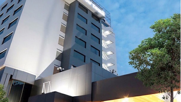 Een modern hotel met een uniek architectonisch ontwerp, met een opvallende glazen gevel en een trap die naar de ingang leidt.