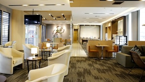 Een moderne hotellobby met zithoeken, een receptiebalie en een bar.