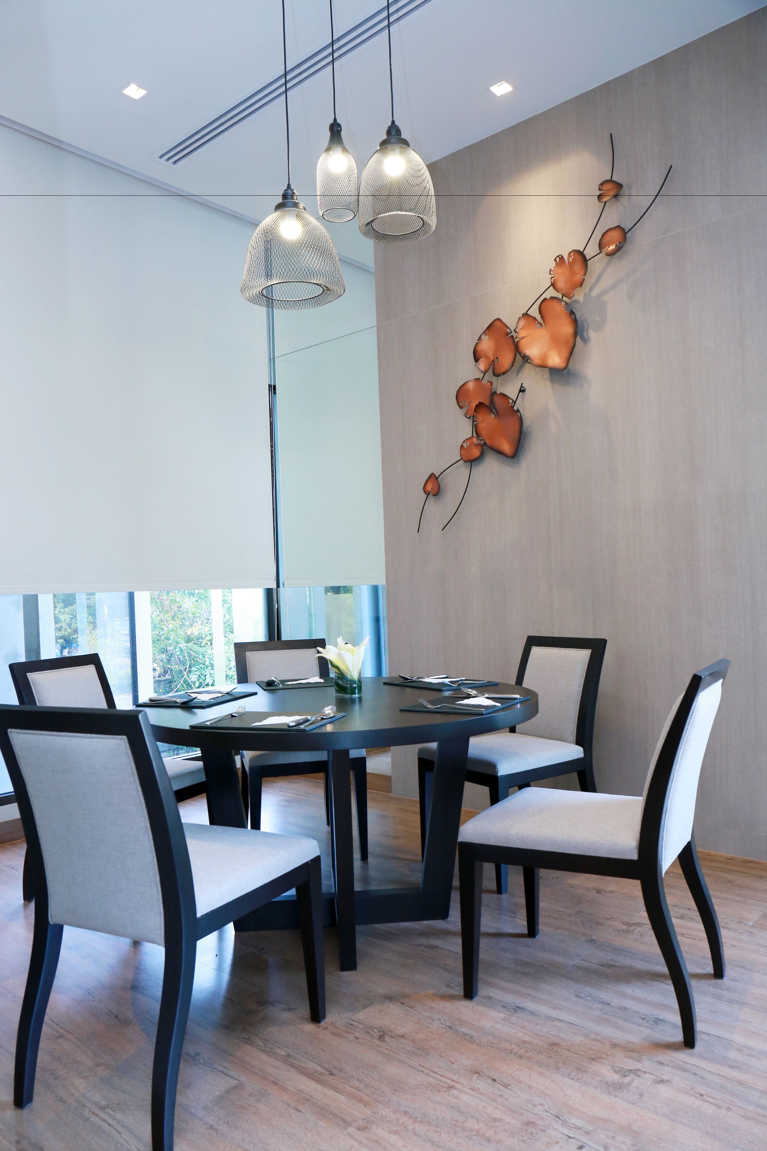 A modern dining area with a round table, six chairs, and pendant lighting.