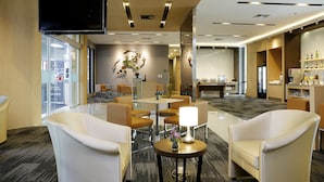 Een moderne hotel lobby met zitgedeeltes, een televisie en een bar.
