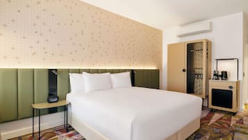 Habitació d'hotel amb un llit gran, una taula de nit, un armari i una catifes amb disseny.