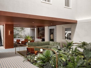 A modern outdoor living area with a green sofa, wooden chairs, and potted plants. - Novotel St Kilda (St Kilda)