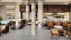 A modern interior with high ceilings, large columns, a central round table, and a bar area. - Novotel St Kilda (St Kilda)