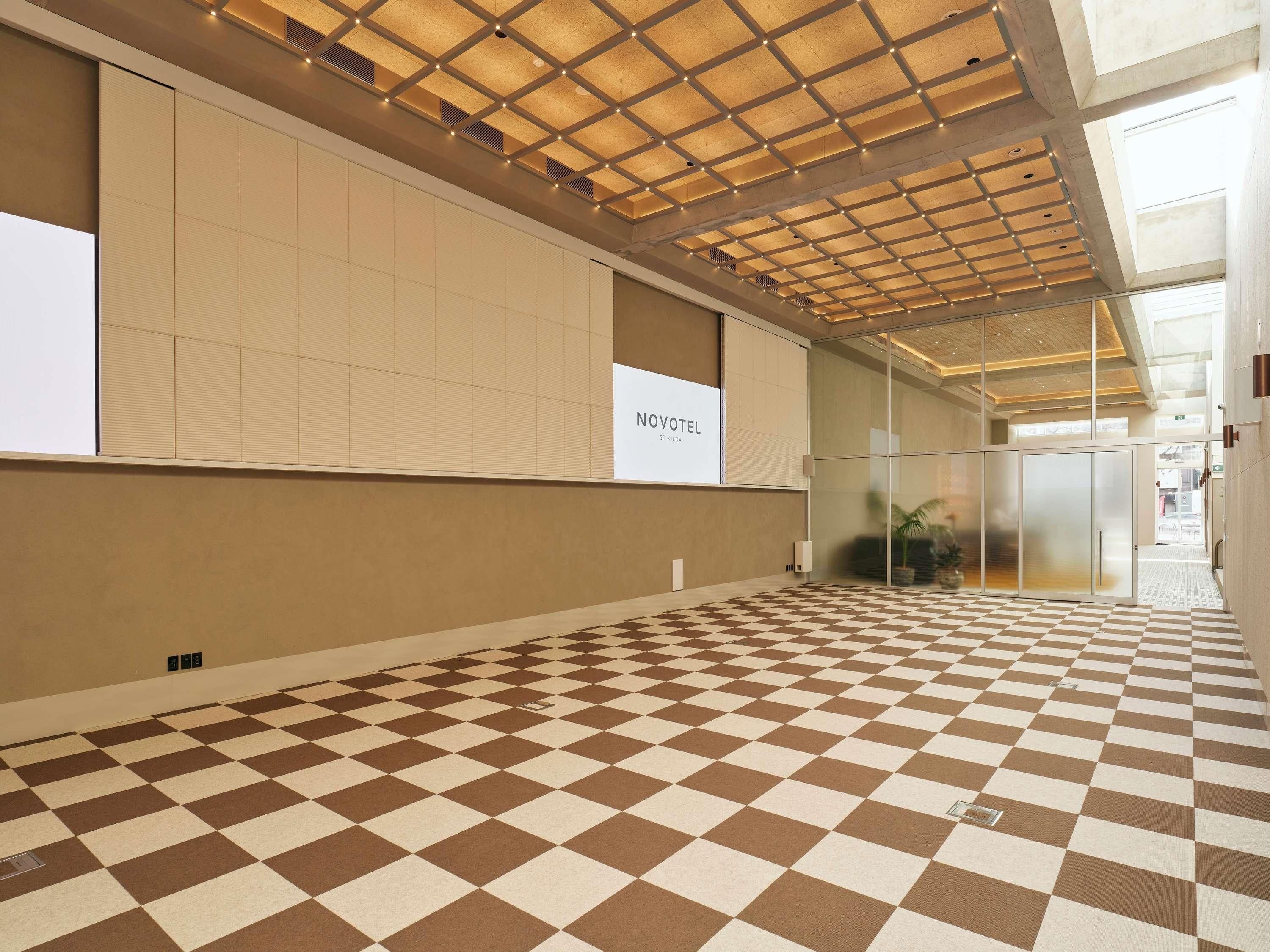 A hotel lobby with a checkered floor, a glass wall, and a ceiling with a grid pattern.