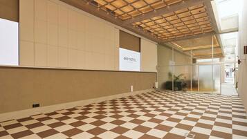 A hotel lobby with a checkered floor, a glass wall, and a ceiling with a grid pattern.