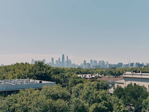 A city skyline with high-rise buildings, a rooftop with air conditioning units, and dense green trees in the foreground. - Novotel St Kilda (St Kilda)