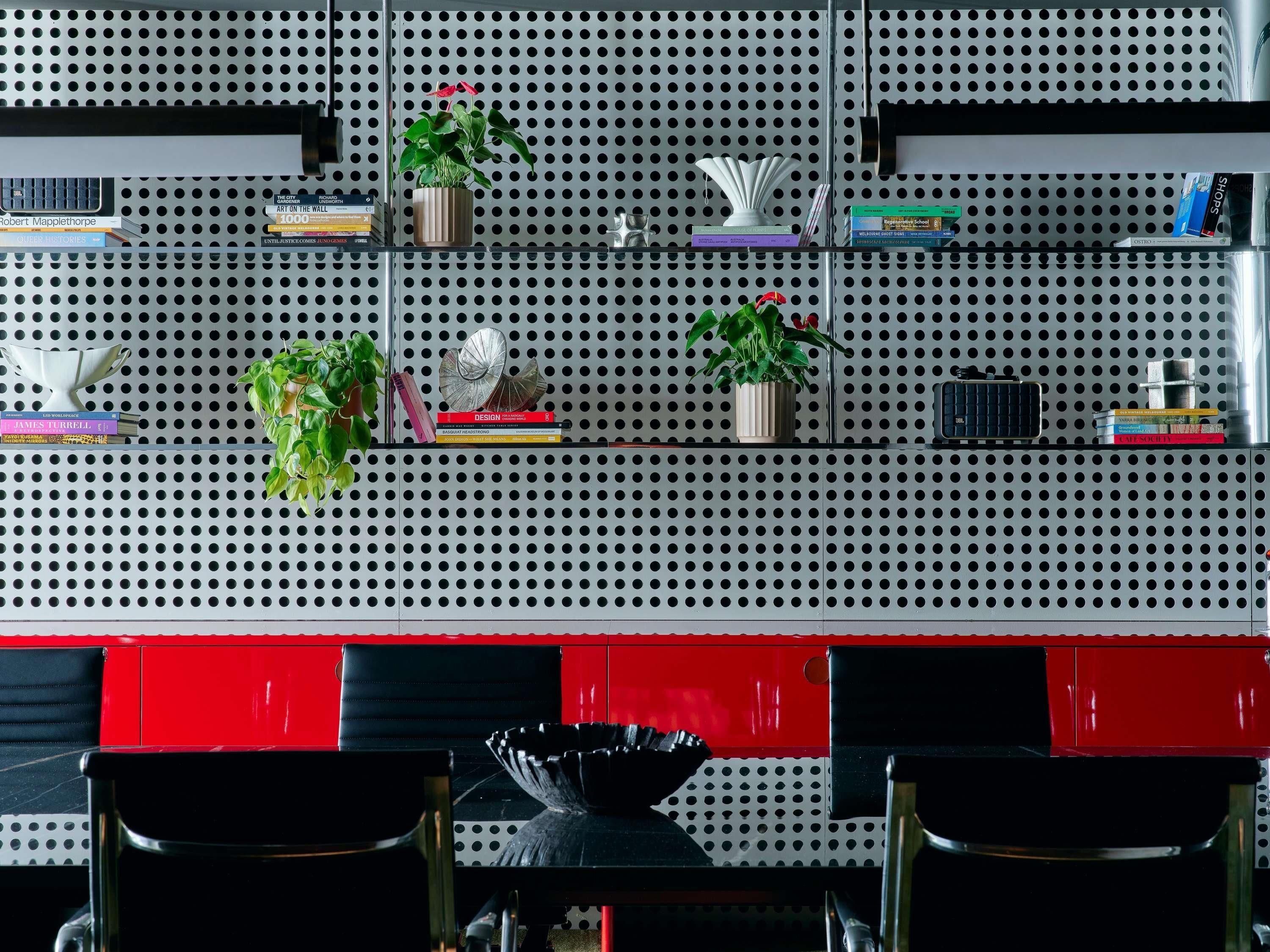 A pegboard wall with shelves holding books, a potted plant, and decorative items.