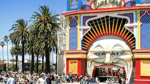 A colorful entrance with a large mural, palm trees, and a crowd of people. - Novotel St Kilda (St Kilda)