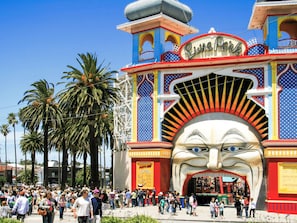 Una entrada colorida con un mural grande, palmeras y una multitud de personas.