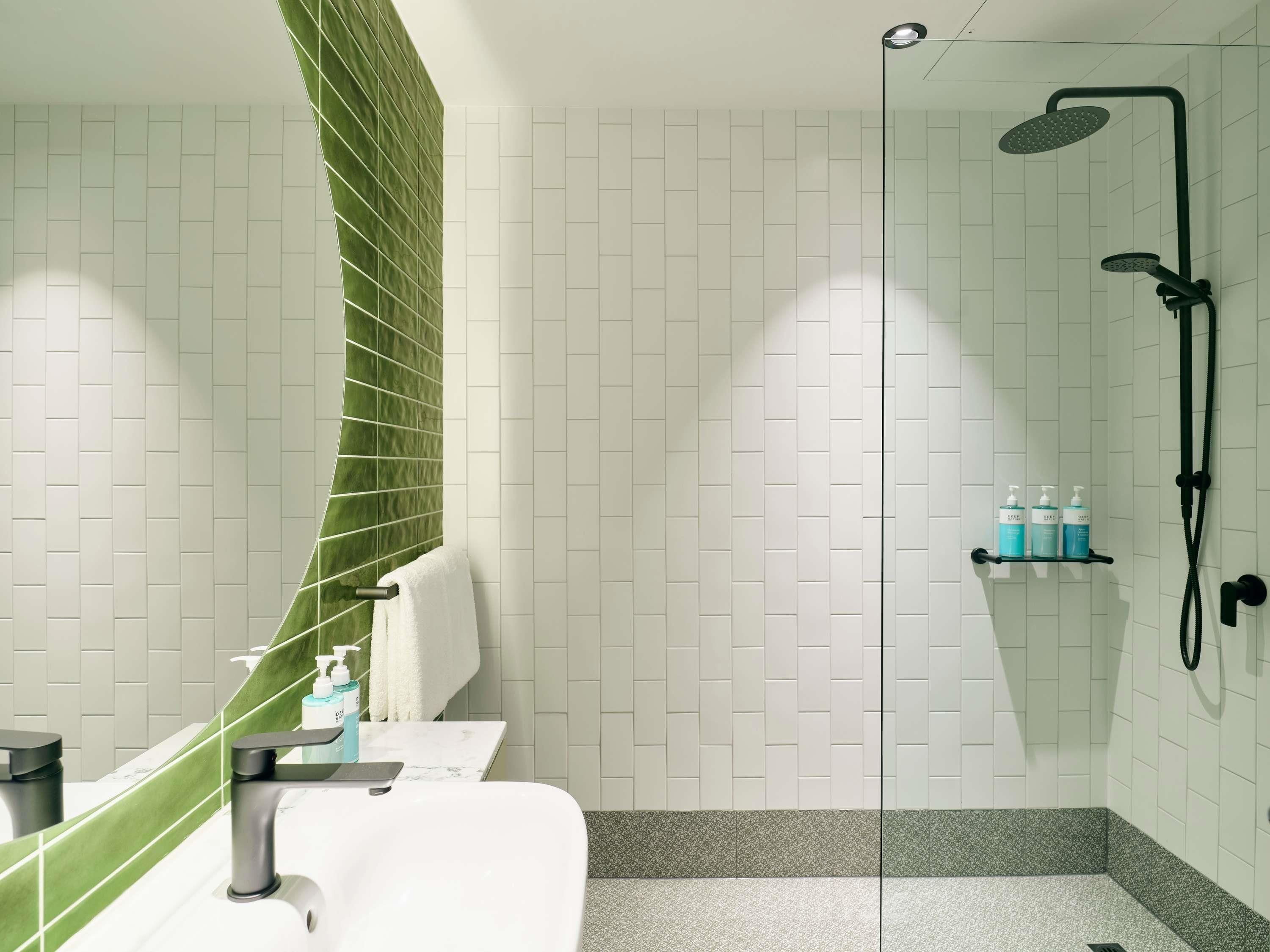 A modern bathroom with a shower, a sink, and a towel rack.
