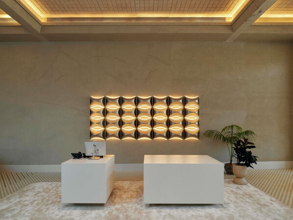 A reception area with a modern design, featuring a wall-mounted light panel and two white reception desks.