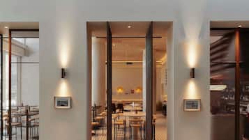A modern interior with a central open space, framed by walls with light fixtures and framed pictures.