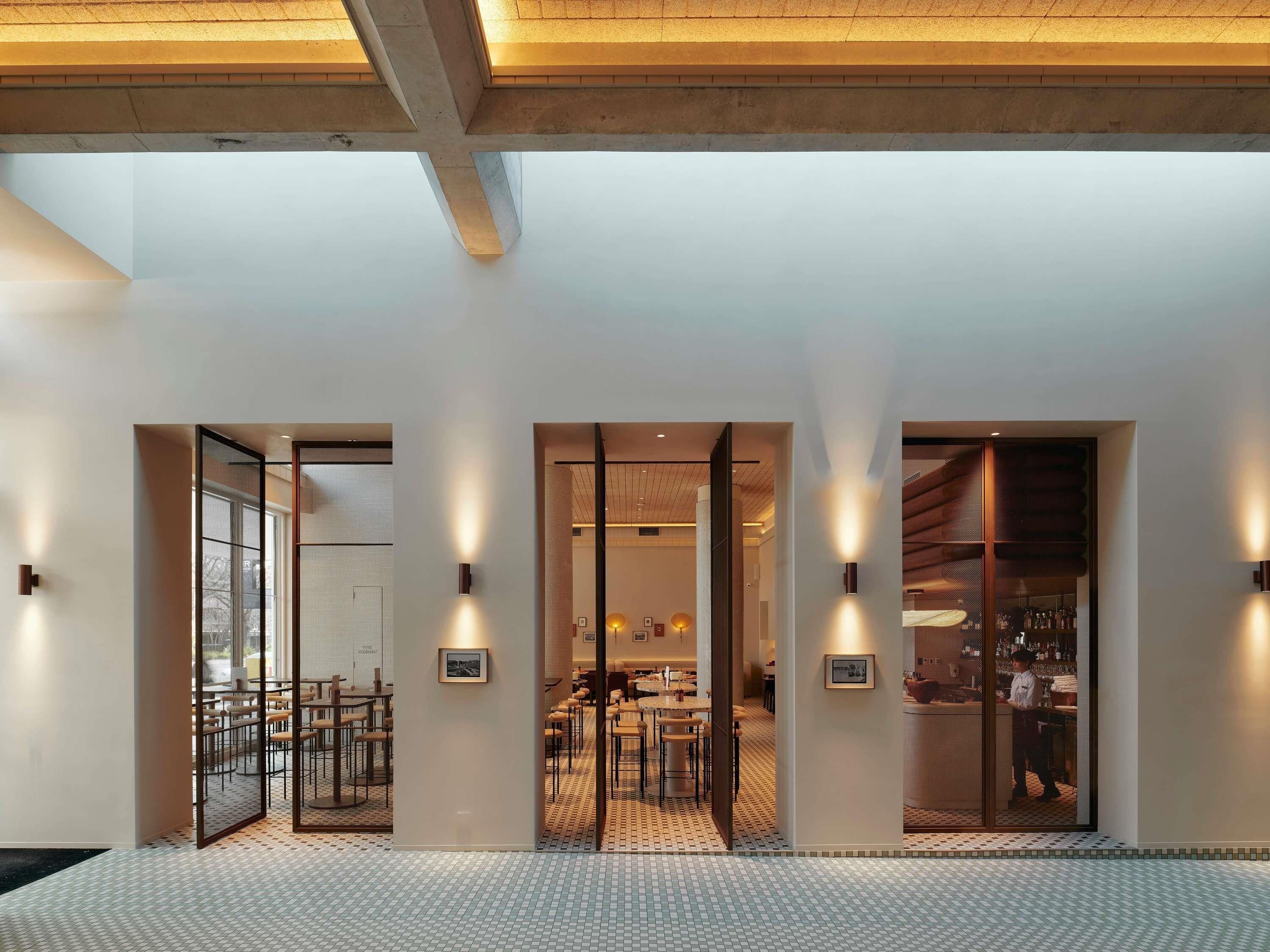 A modern interior with a reception area, dining space, and bar.