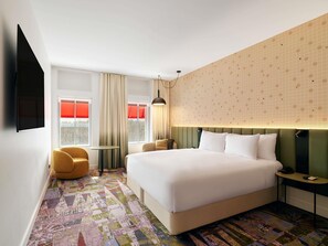 A hotel room with a large bed, a desk, a chair, and a TV. - Novotel St Kilda (St Kilda)
