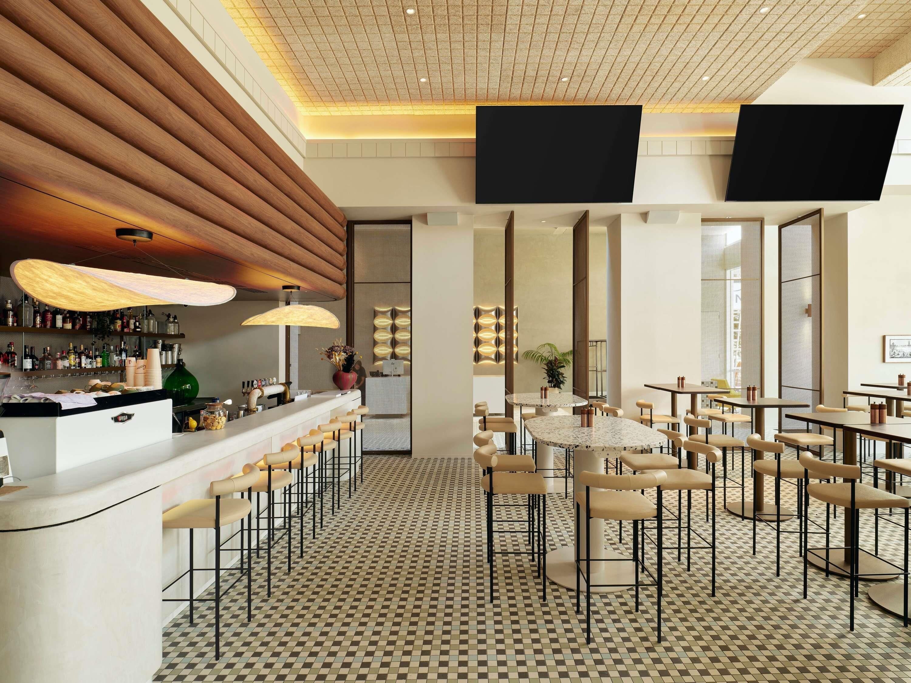 Un espace bar moderne avec un sol à carreaux, des tabourets de bar et une variété de bouteilles exposées sur des étagères.