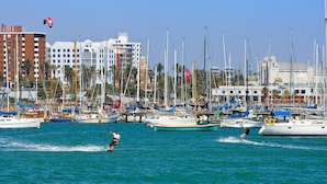 A marina with multiple boats docked, a person wakeboarding, and buildings in the background. - Novotel St Kilda (St Kilda)