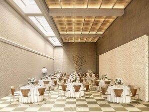 Ein geräumiger Festsaal mit mehreren runden Tischen, jeder Tisch mit weißer Tischdecke und Blumenarrangements dekoriert.