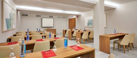 A conference room with multiple tables, chairs, water bottles, and a whiteboard.