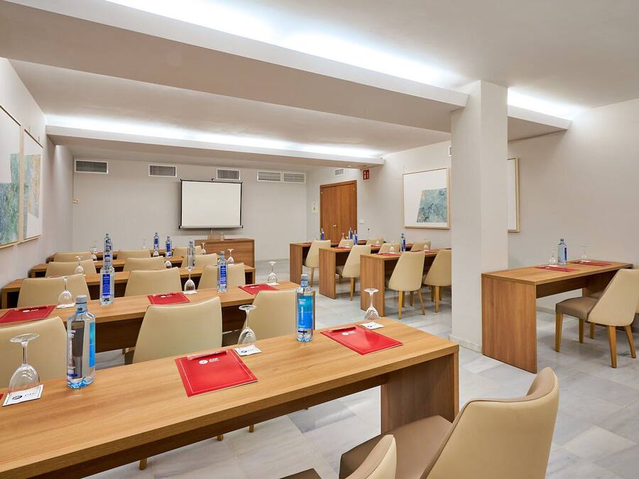 A conference room with multiple tables, chairs, water bottles, and a whiteboard.