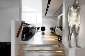 A modern interior with a staircase leading to a seating area, a large metallic sculpture, and a view through a window. - 101 Hotel, Reykjavik, a Member of Design Hotels (Reykjavik)