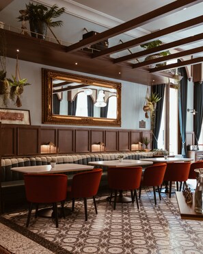 Ein Restaurant mit einer langen Theke, Sitzecken und roten Stühlen.