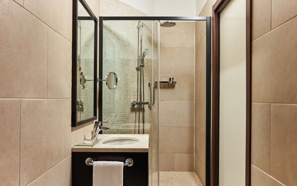 A modern bathroom with a glass-enclosed shower, a sink with a mirror, and a towel hanging on a rack.