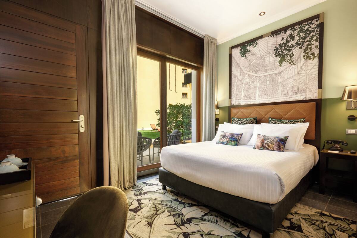 Une chambre d’hôtel avec un grand lit, une porte en bois, une vue sur l’extérieur et une carte accrochée au mur.