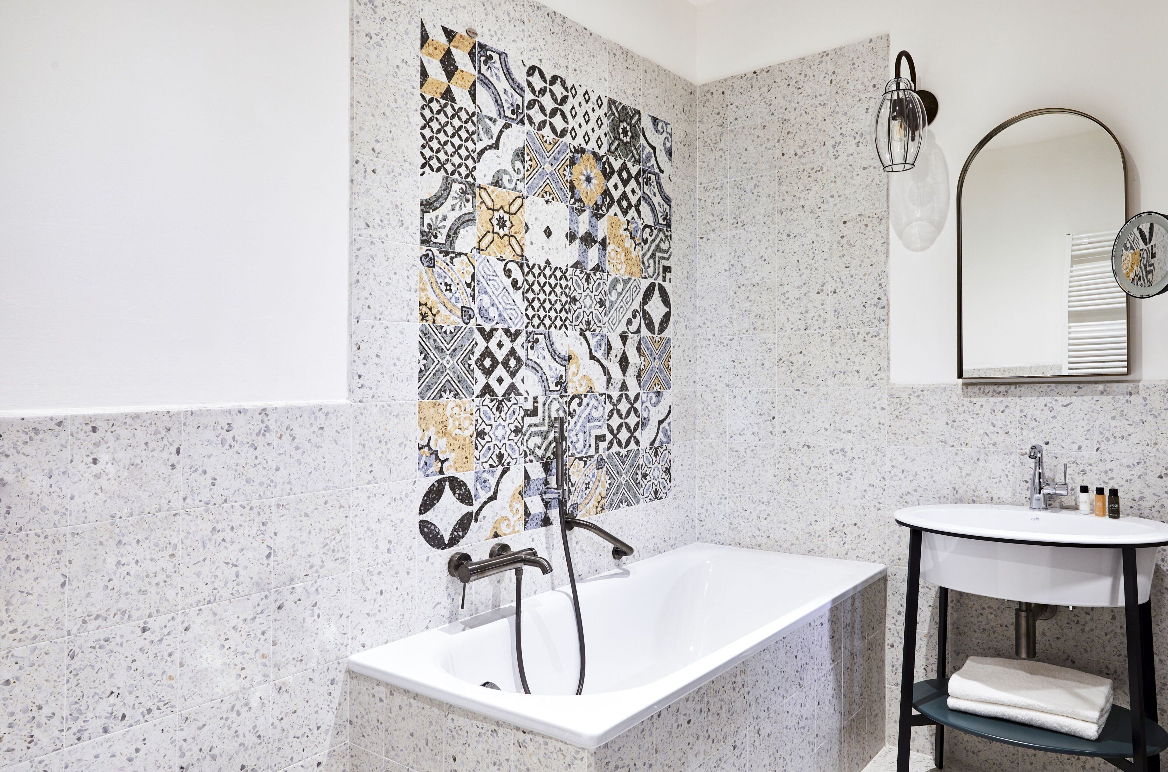 Ein Badezimmer mit freistehender Badewanne, einem wandmontierten Waschbecken und einer dekorativen Fliesenrückwand.