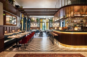 Een bar met een gebogen toonbank, diverse zitplaatsen zoals zitjes en tafels, en een vloer met een patroon.