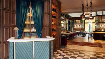 A hotel lobby with a checkered floor, a bar area, and a seating section.