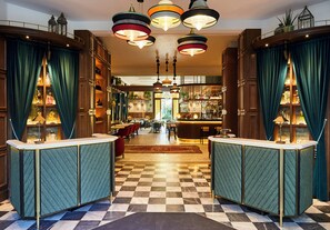 Een hotellobby met zwart-witte vloertegels, een bar en een receptiebalie.