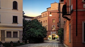 Une rue étroite, bordée de bâtiments des deux côtés, avec un arbre au milieu et une plaque indiquant « Calle Rovereto ».
