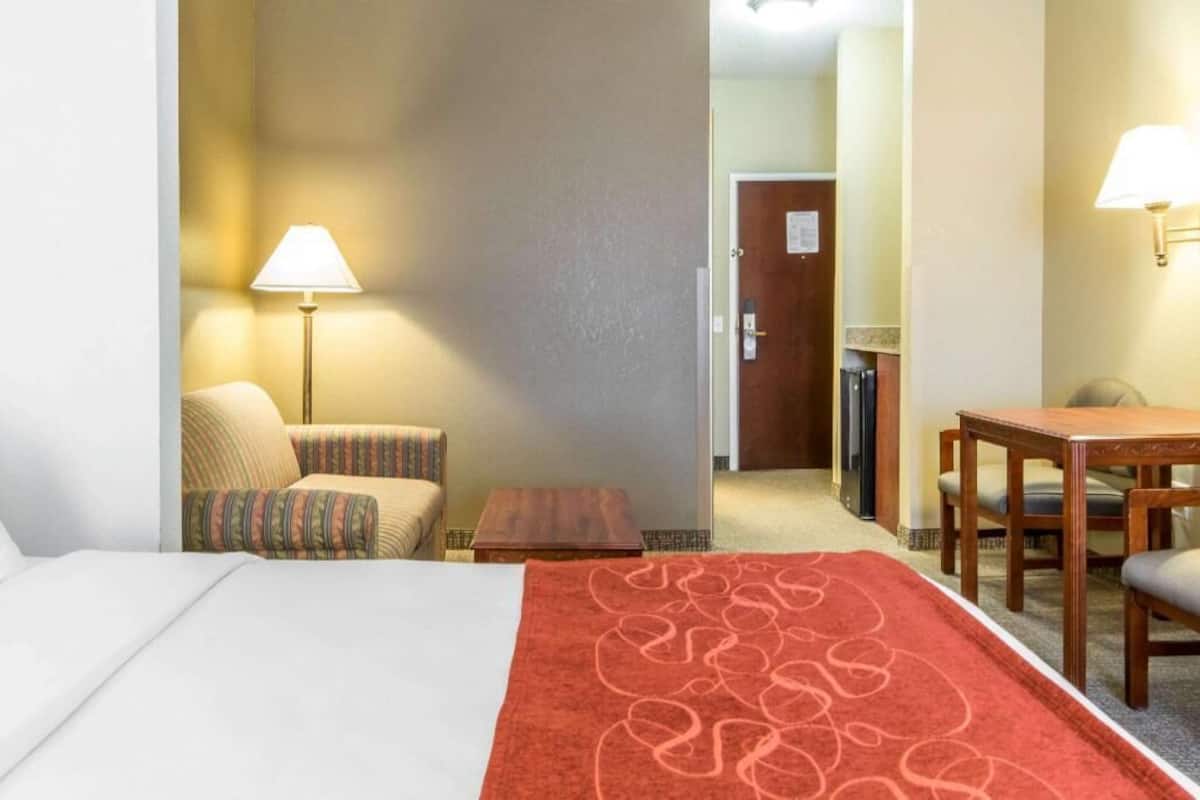 Une chambre d’hôtel comprenant un lit, une chaise, une petite table, une lampe et une table à manger avec des chaises.