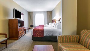 A hotel room with a bed, a sofa, a TV, a desk, and a dresser.