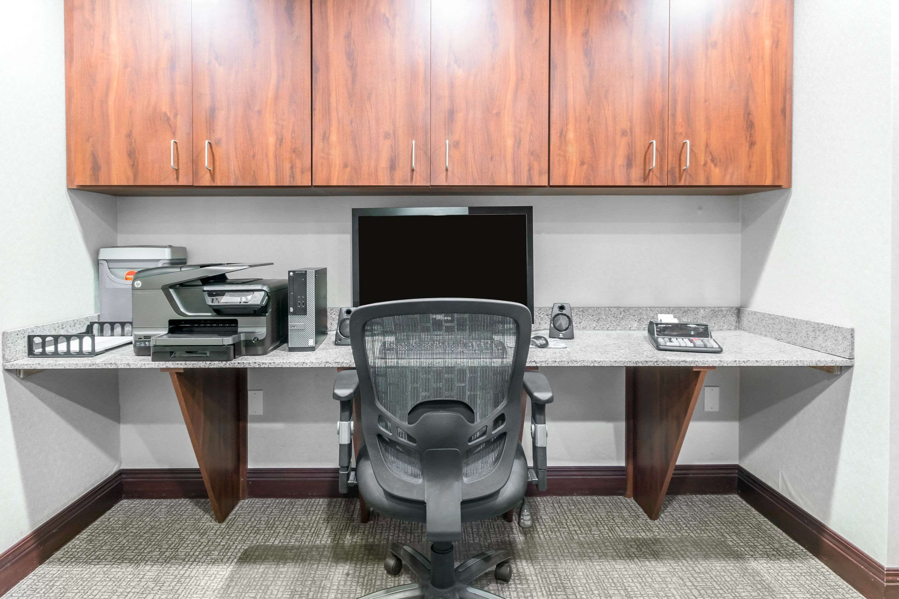 Un bureau d’angle équipé d’un bureau, d’un ordinateur, d’une imprimante et d’une chaise.