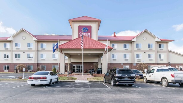A Comfort Suites hotel with a red roof, multiple parking spaces, and a flag in front.
