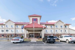 Un hôtel Comfort Suites avec un toit rouge, plusieurs places de stationnement et un drapeau devant.