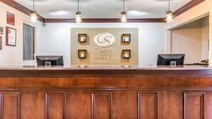 A reception desk with a wooden panel and a sign reading "Comfort Suites".