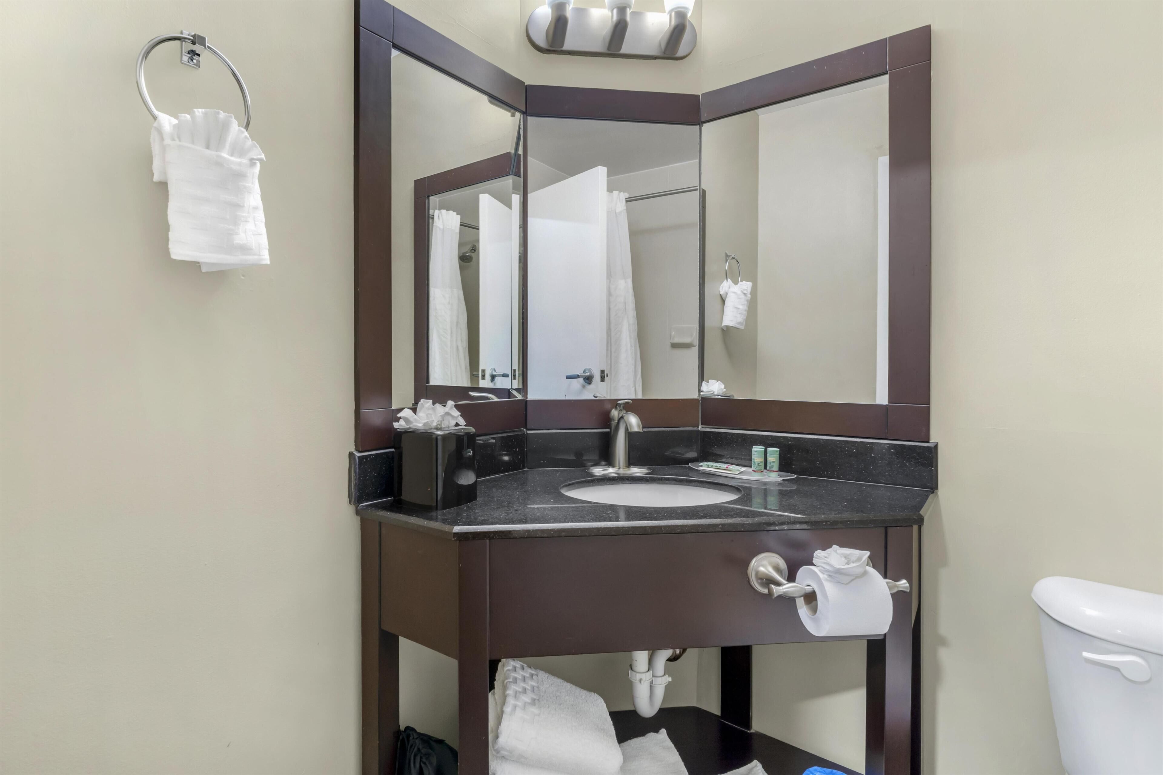 A bathroom with a sink, mirror, towel rack, and toilet.