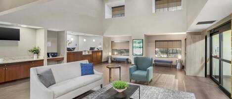 A spacious living area with a sofa, coffee table, and a view of the kitchen and dining area.