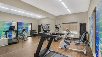 Un gimnasio con cintas de correr, elípticas y equipo de pesas.