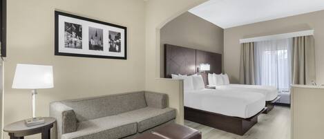 Una habitación de hotel con cama, sofá, una mesita y un cuadro en la pared.