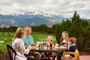 Una familia cenando en una mesa con vistas a la montaña.