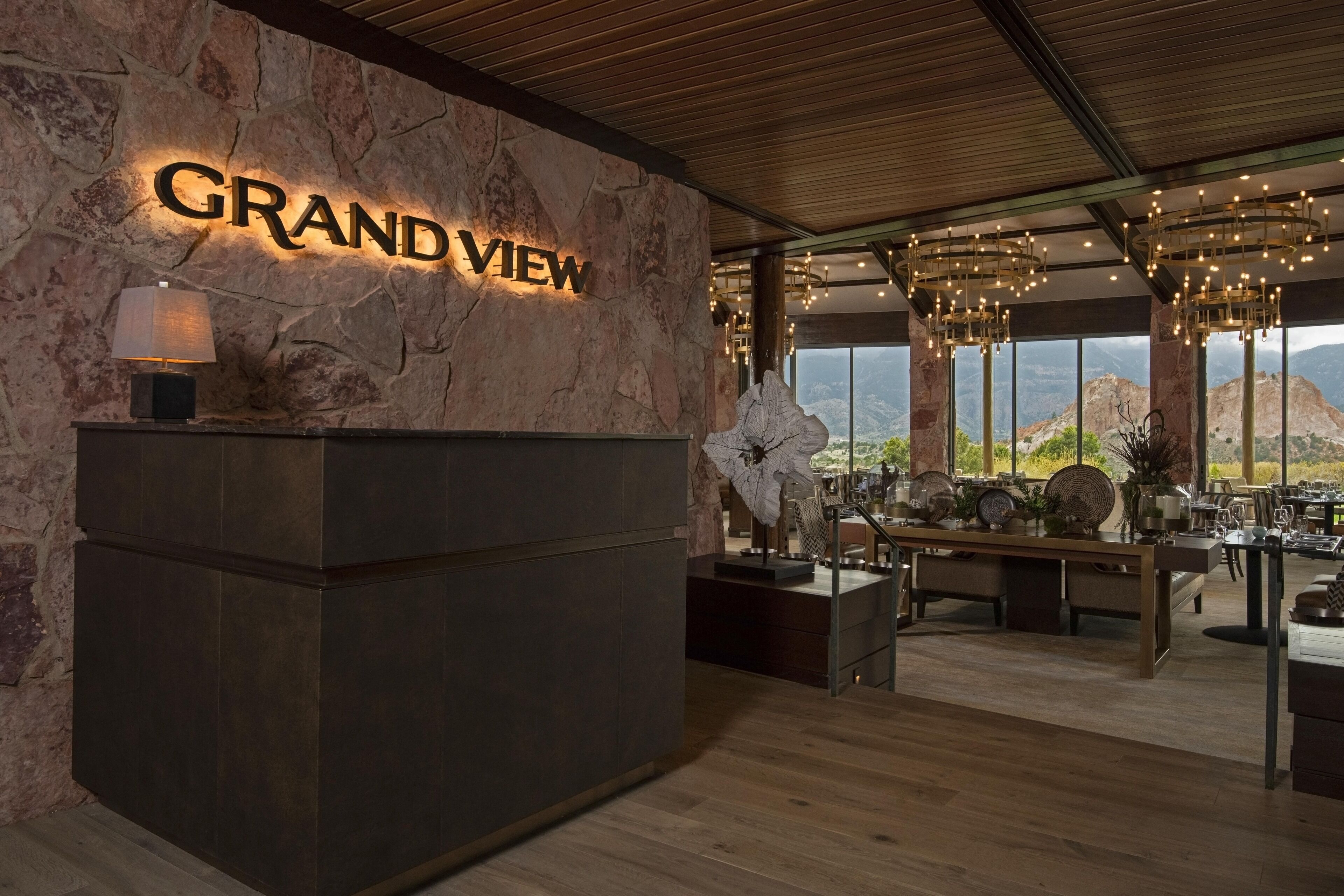A reception area with a stone wall, a 'GRAND VIEW' sign, a reception desk, and a seating area with a view of the mountains.