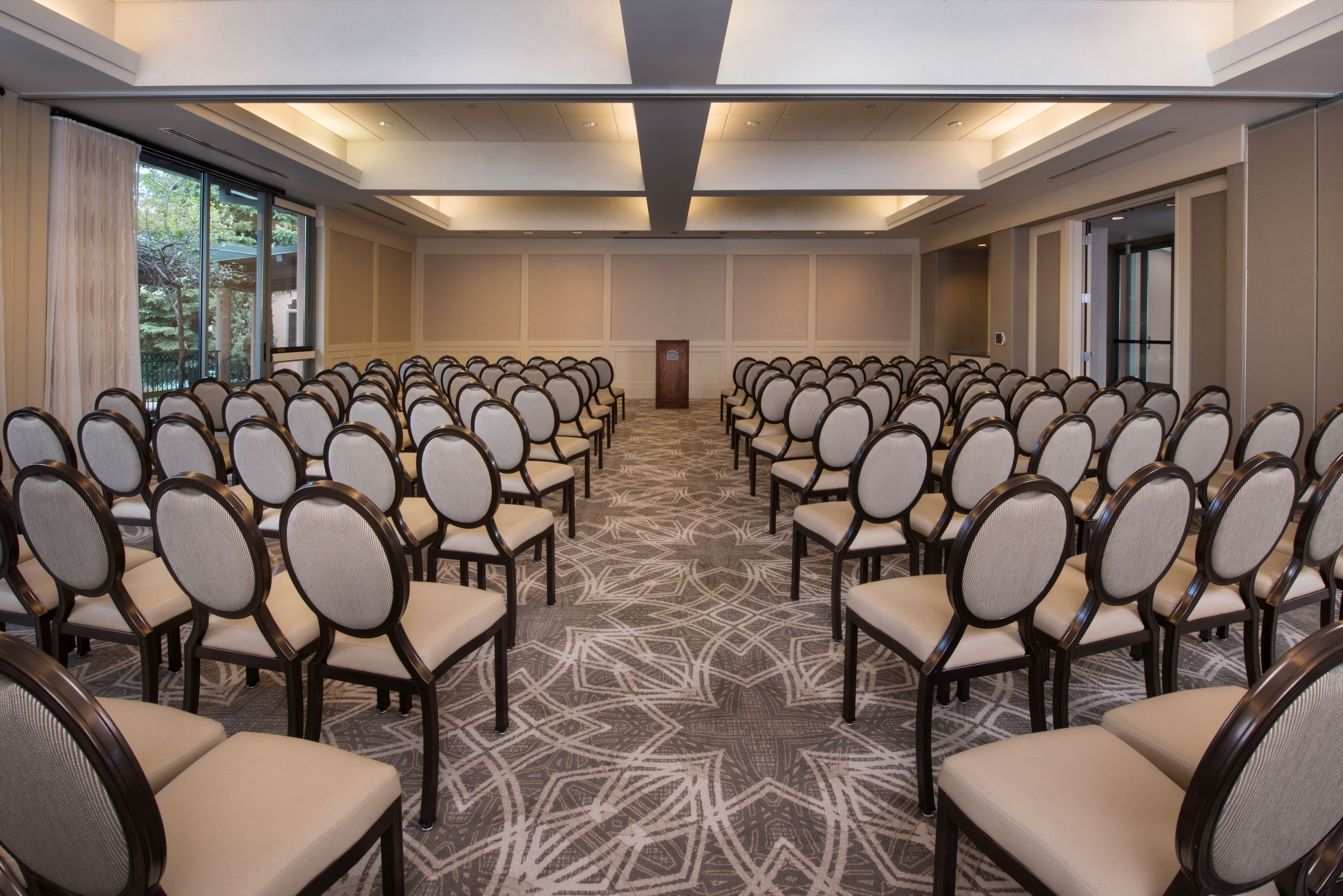 A conference room with rows of chairs, a podium, and large windows.