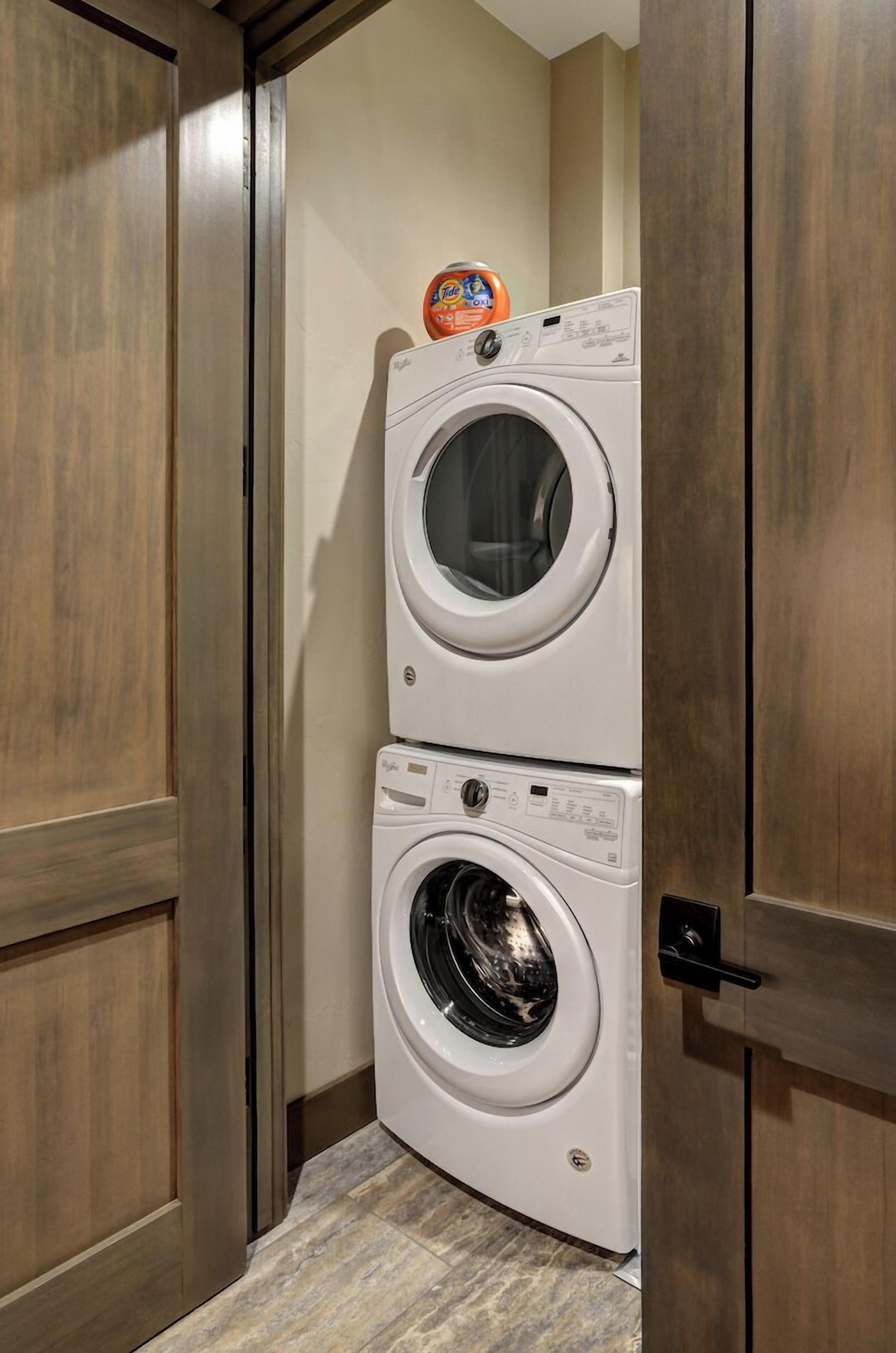 A laundry room with two stacked front-loading washing machines and a detergent dispenser on top.